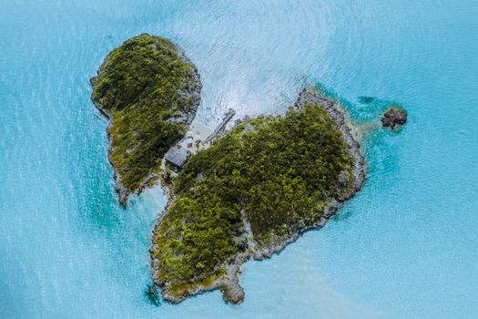 Stunning aerial view of a lush, remote tropical island surrounded by turquoise waters.