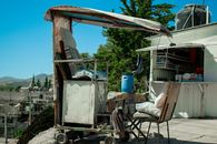 An outdoor shoe shine setup with rustic chairs and cart on a sunny day.