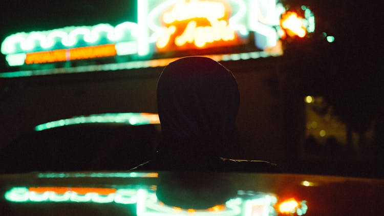 Person In Hood On Illuminated Night Street