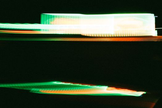 Blurry neon lights creating an abstract dynamic design in dark setting.