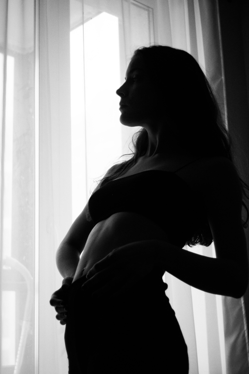 Free Artistic silhouette of a woman posing gracefully by a window in black and white. Stock Photo