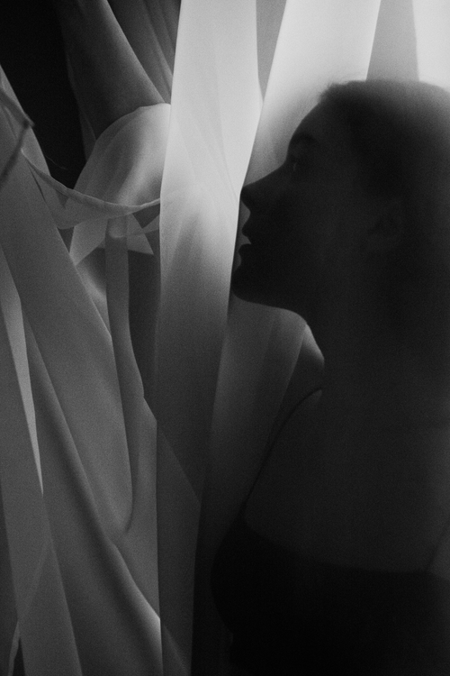 Free Silhouette of a woman beside flowing fabric in a black and white artistic portrait. Stock Photo