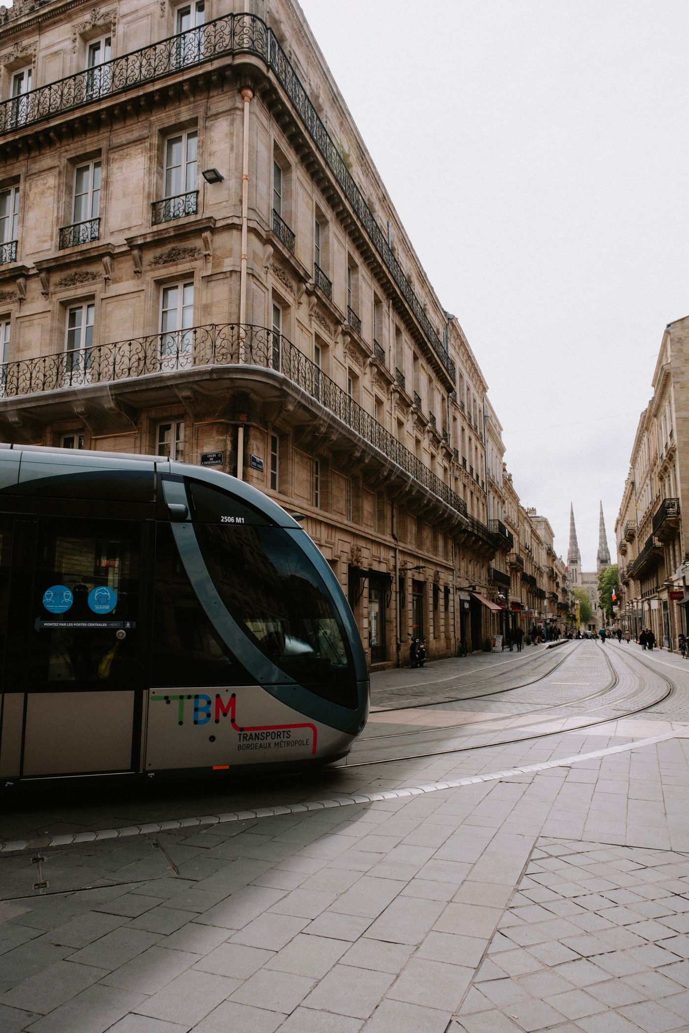 Un tramway circule dans une rue de Bordeaux bordée d'immeubles anciens