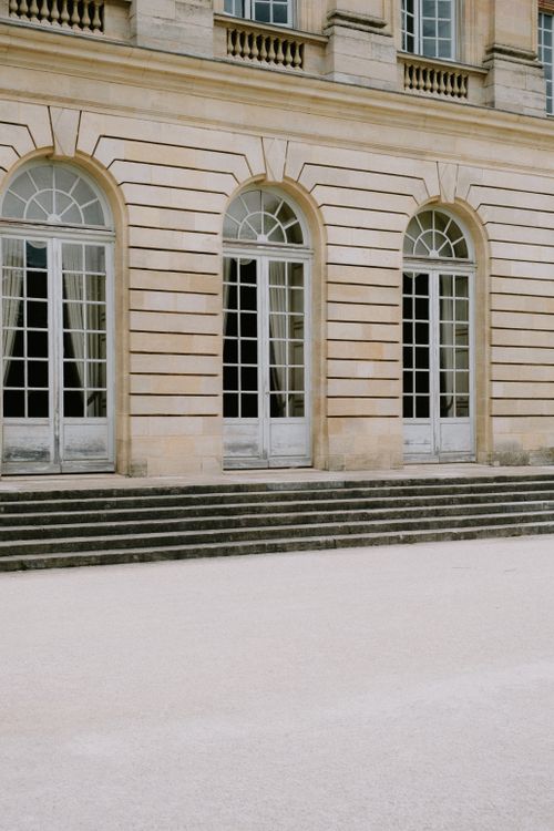 Free Elegant facade of a European building with arched windows and stone steps, showcasing classic architectural design. Stock Photo