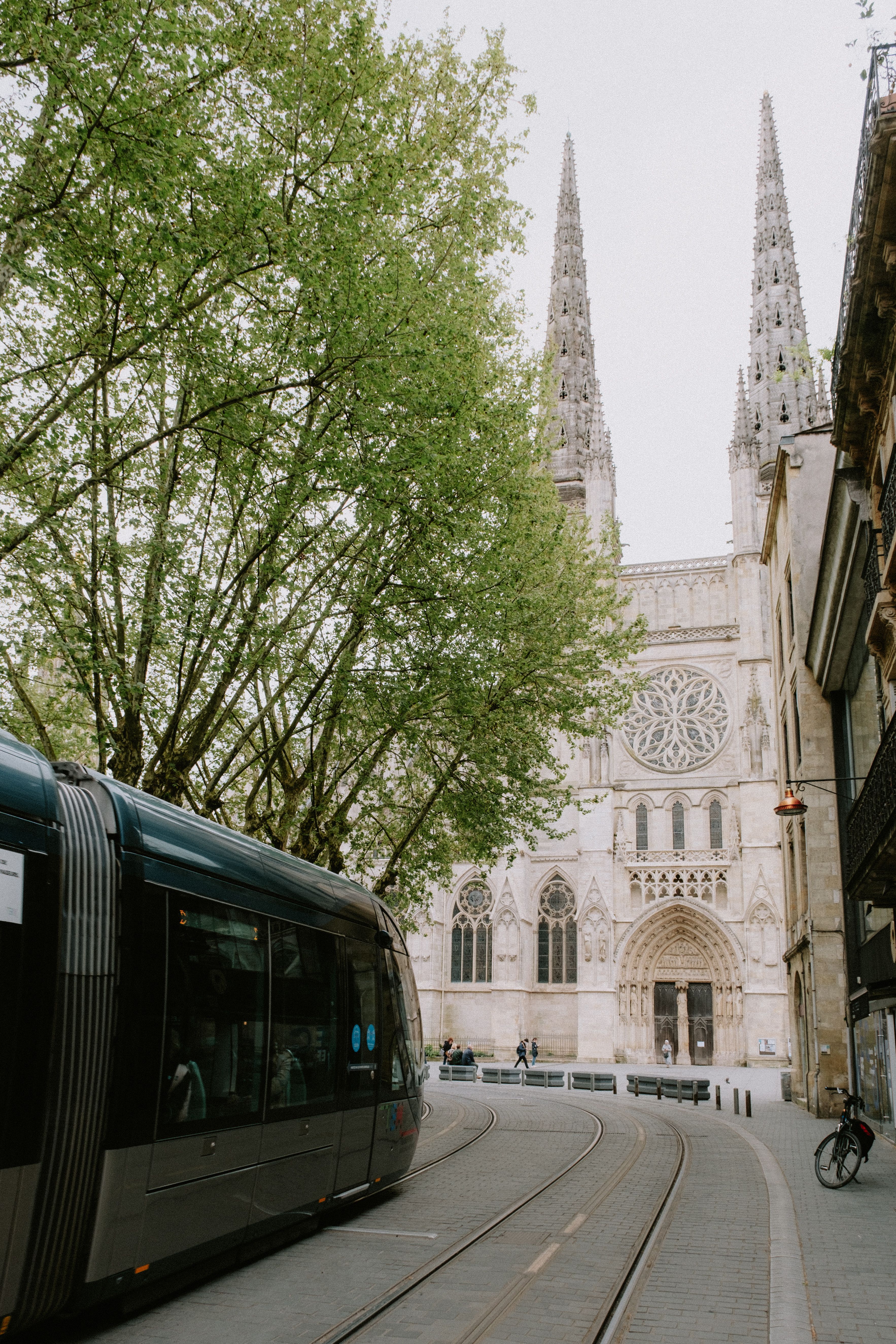 Fotomural Un tranvía moderno deslizándose junto a la histórica Catedral de Burdeos en una escena urbana.