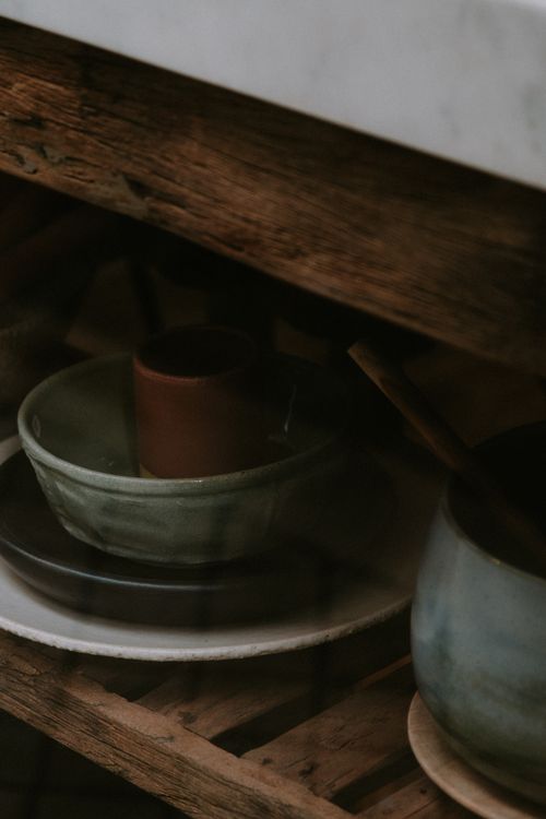 Pottery plates and bowls displayed on a rustic wooden shelf — photo by Mathias Reding on Pexels