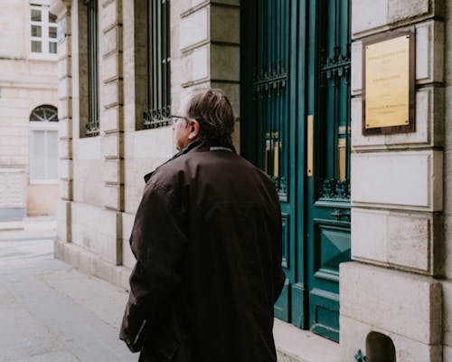 Man in Brown Coat Standing Near Blue Door