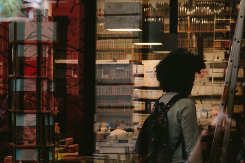 Free Silhouette of a woman in a bookstore with books and reflections. Stock Photo