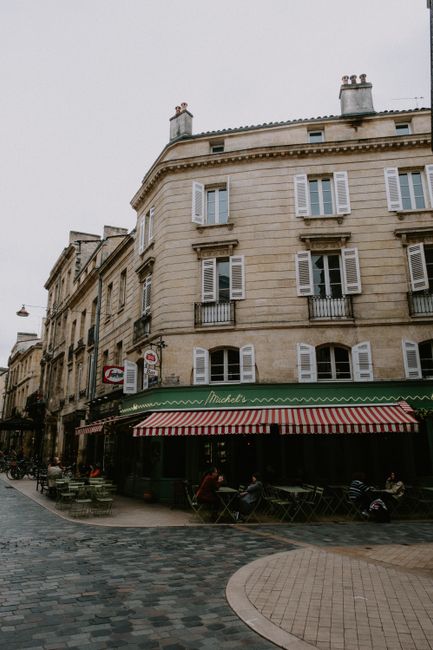 A bustling urban street scene with historic architecture and a cozy sidewalk cafe in Europe.