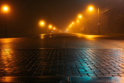 Free Empty street illuminated by streetlights on a misty night, capturing a serene urban atmosphere. Stock Photo