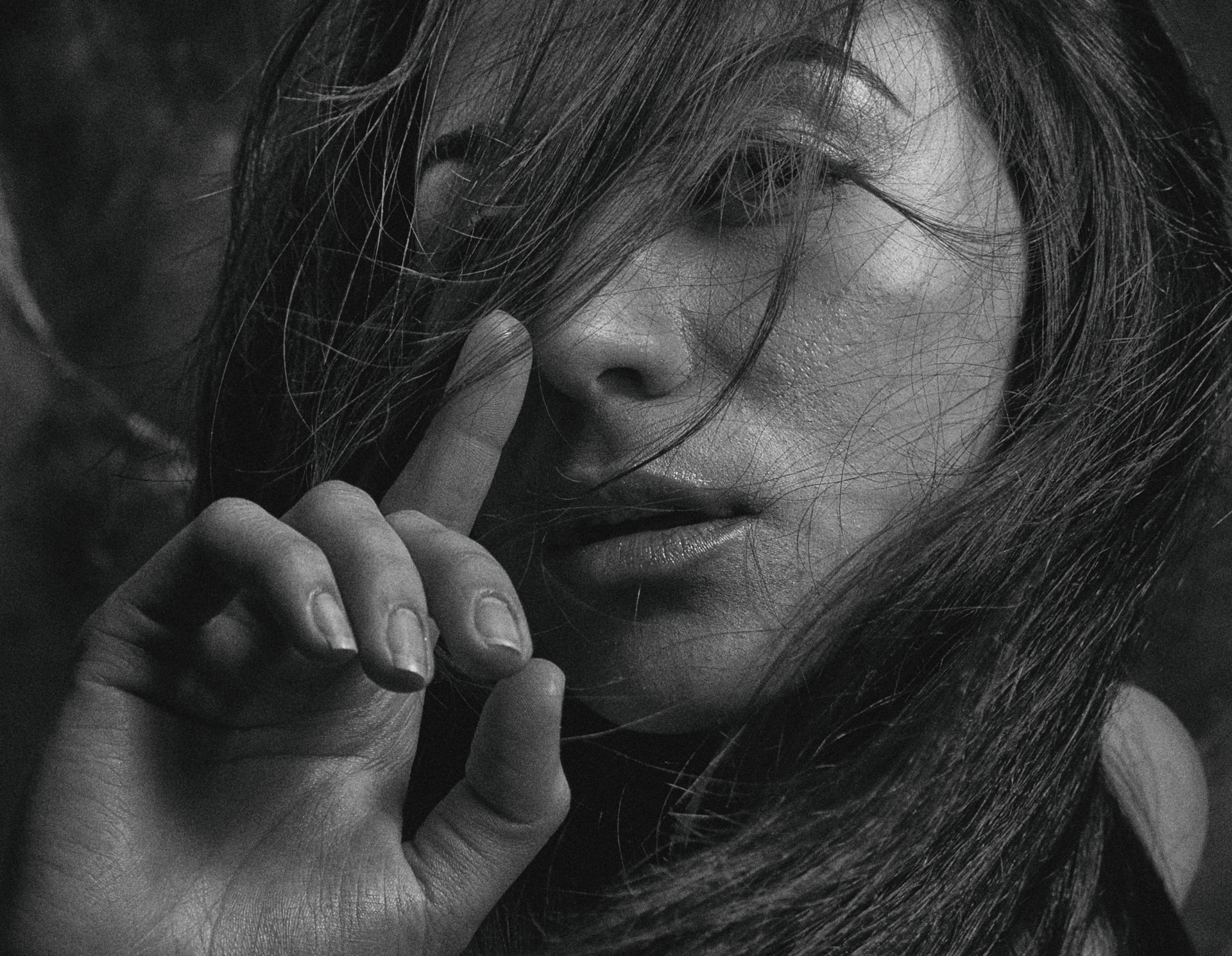 Artistic black and white close-up portrait of a woman with flowing hair, evoking mystery.