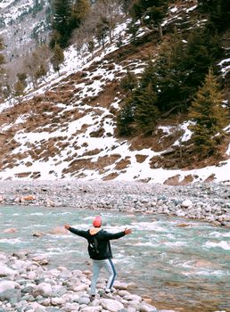 A traveler enjoys the scenic mountain stream surrounded by snow and rocks in Pakistan.