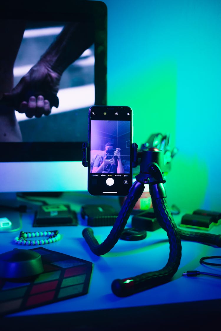 Phone Propped On Camera Holder On Desk Illuminated With Neon Light