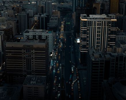 Aerial view of Sharjah cityscape at night with illuminated streets and tall buildings.