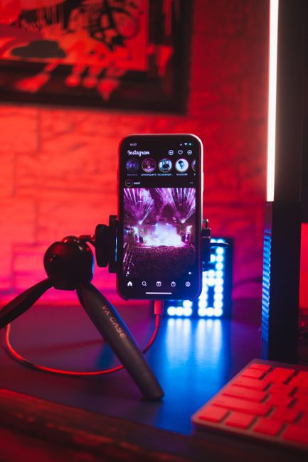 Smartphone on tripod with Instagram visible against vibrant neon backdrop