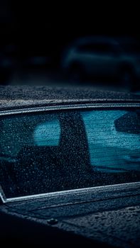 Detailed close-up of raindrops on a classic car's window at night, creating a moody atmosphere.