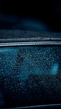 A moody close-up of rain-covered car window at night in Dubai, UAE, creating a mysterious ambiance.