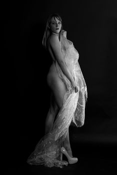 Elegant black and white portrait featuring a woman with tulle and high heels in a studio setting.