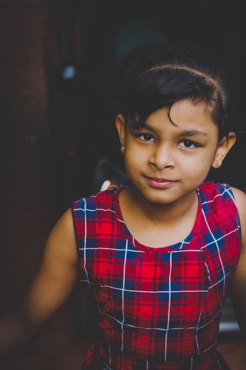 Free Charming portrait of a young girl in a red tartan dress with a gentle smile. Stock Photo