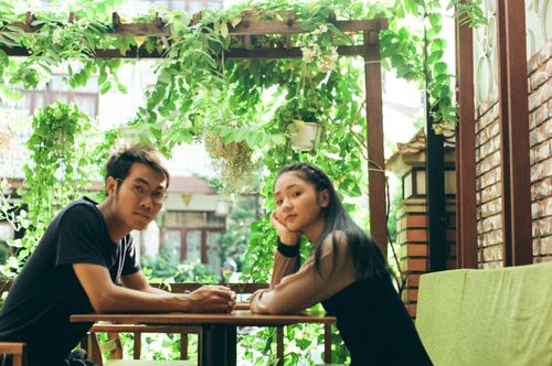 Free Asian couple enjoying a serene moment sitting together in a lush garden setting. Stock Photo