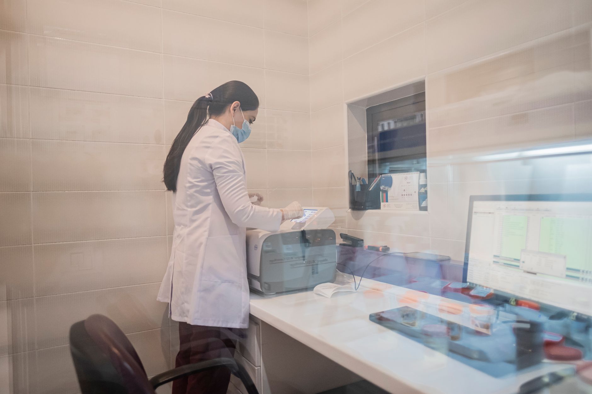 Woman in a lab coat examines equipment in a laboratory environment, Baku, Azerbaijan.