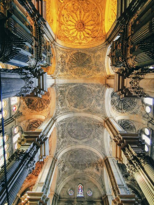 Free View of ornate ceiling inside a historic Spanish cathedral with detailed pillars. Stock Photo