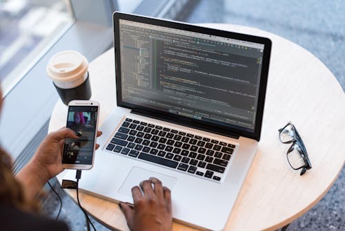 Person Hold Gold Htc Android Smartphone in Front of Macbook Pro