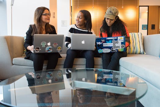 在现代办公环境中，三名女性正使用笔记本电脑进行工作讨论