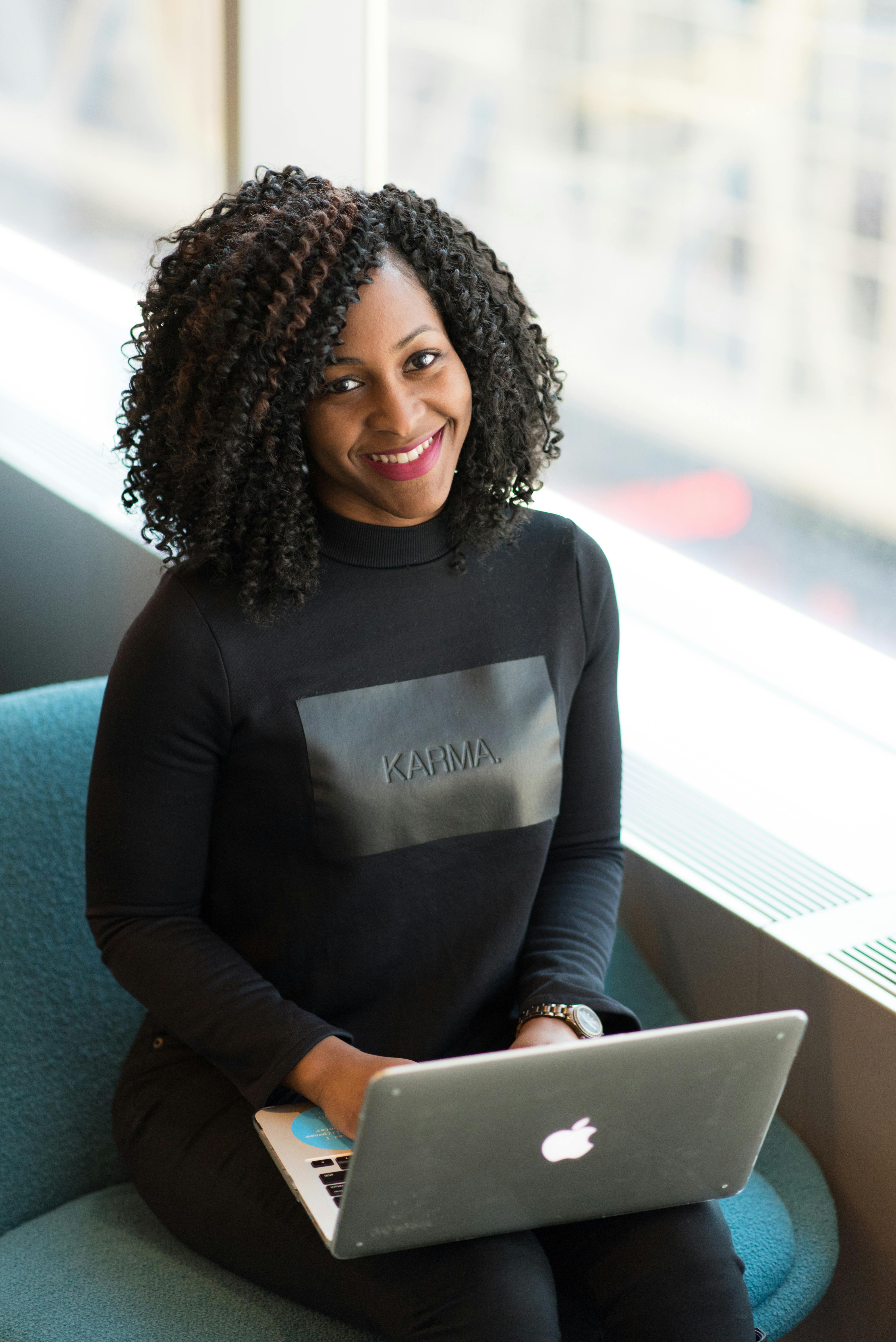 woman wearing black sweatshirt using silver macbook