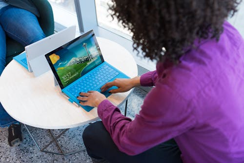 Pessoa Usando Laptop Azul Sentada Ao Lado Da Mesa