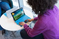 Person Using Blue Laptop Sitting Beside Table