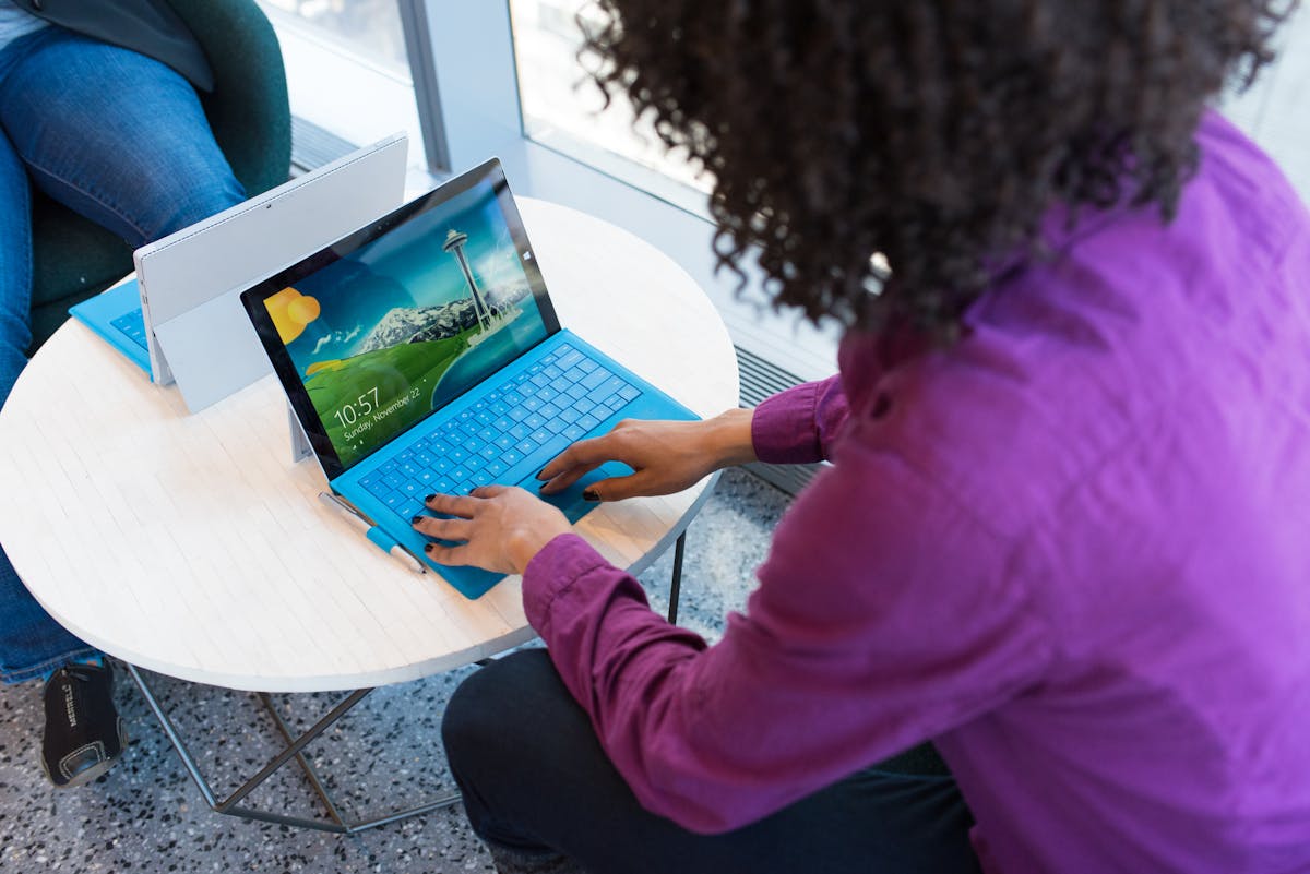 Woman working alone on a colorful laptop in a bright coworking space, showing flexible solo work.