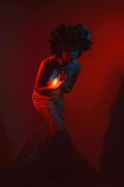 Enchanting artistic portrait of a model with flower crown in moody red light and creative shadows.