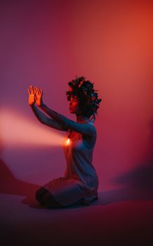 Ethereal artistic portrait of a woman with a flower crown in dramatic red and blue studio lighting.