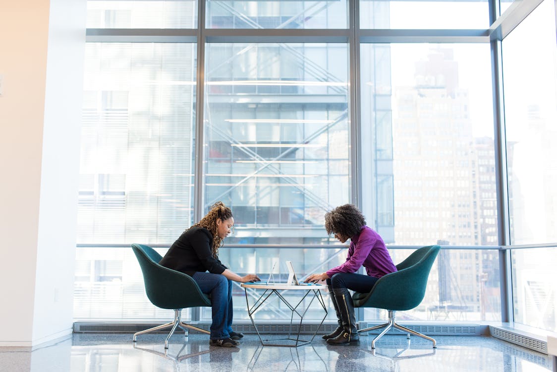 Two Woman Sitting Near Green Padded Chair