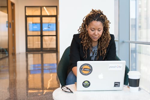 Woman in Black Blazer Sitting on Black Chair Using Laptop