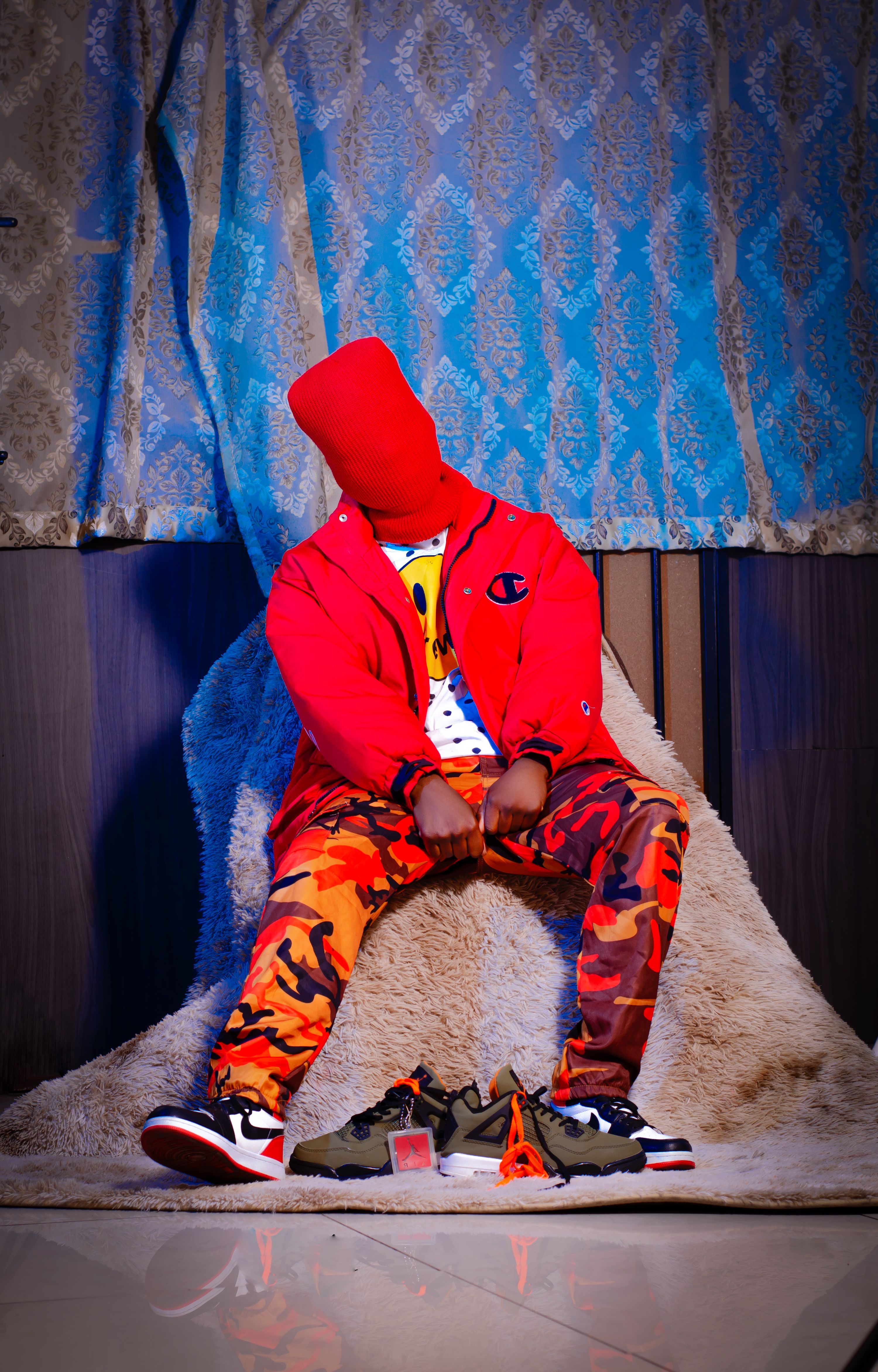 A creative urban fashion photo with a masked model in vibrant attire, taken in a Johannesburg studio.