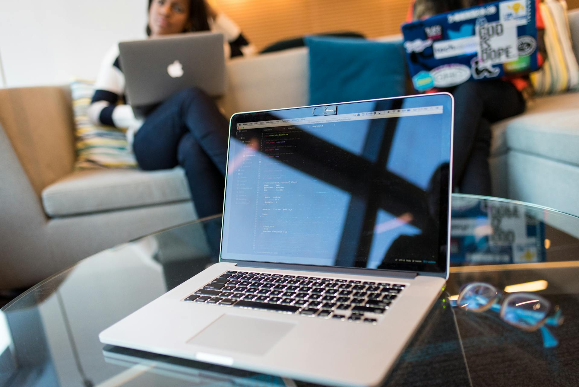 Two people working on laptops in a modern office setting. Technology focus.