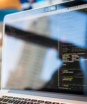 Laptop displaying code with reflection, perfect for tech and programming themes.