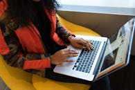 办公室里，一名穿着红色夹克的女士正专注地用笔记本电脑打字