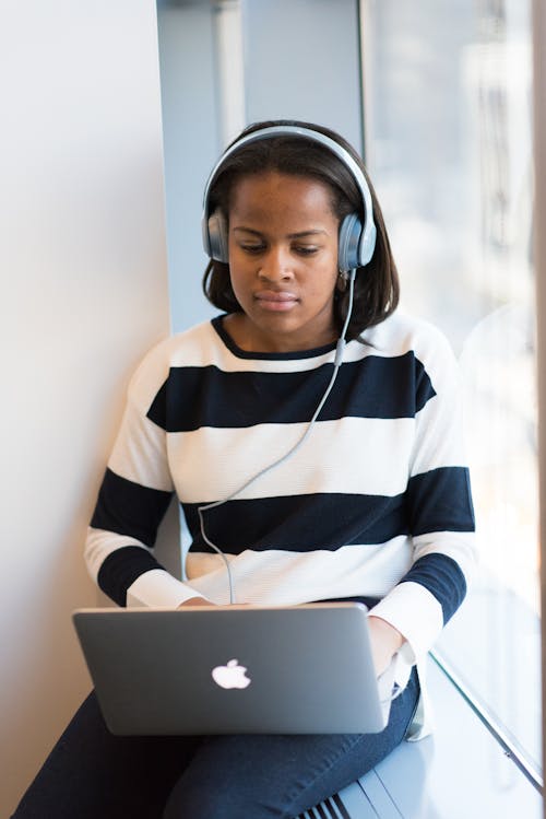 女人通过使用macbook的耳机听