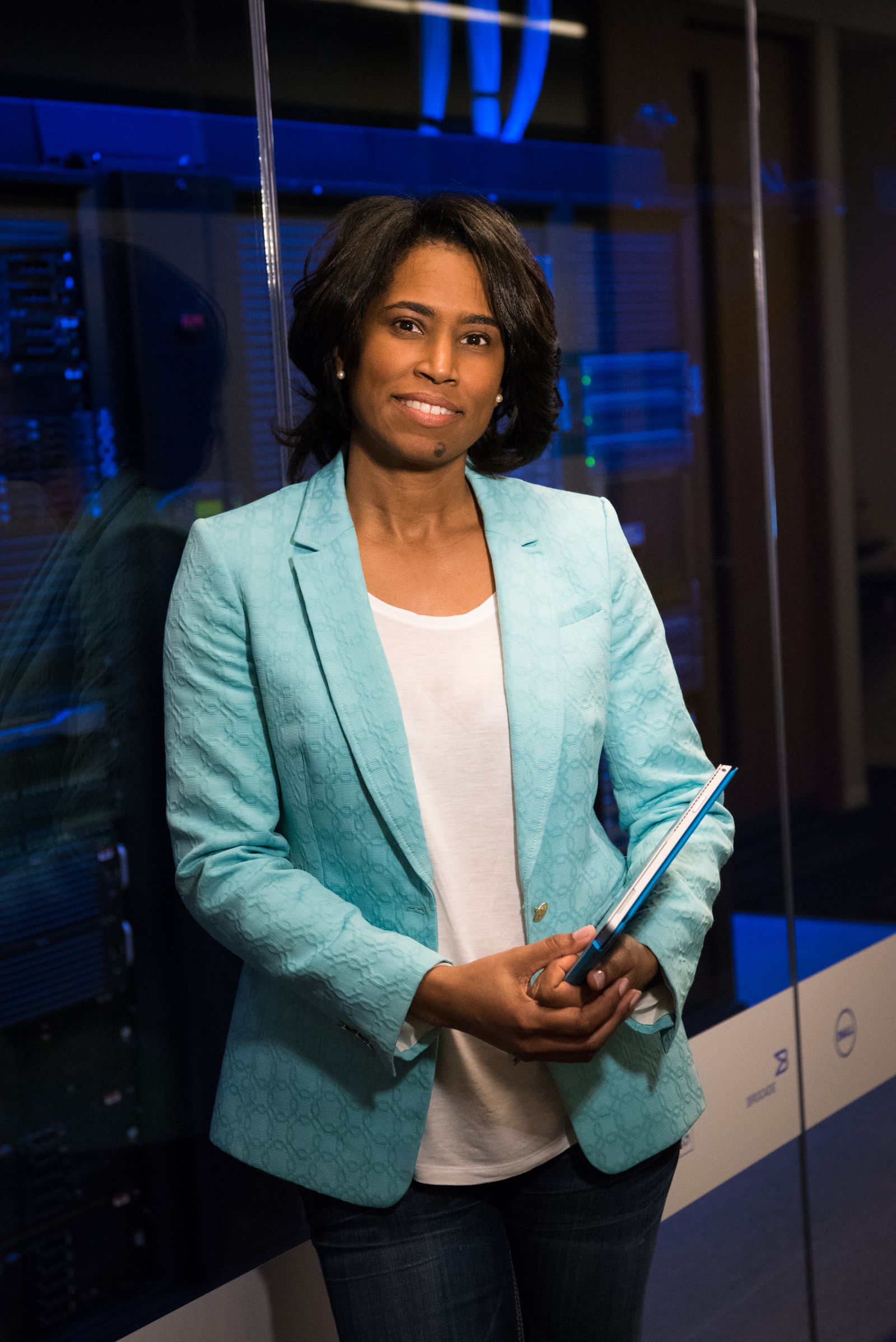 An engineer in a teal jacket standing in a server room