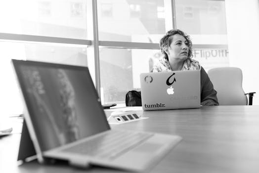Businesswoman using laptop in a bright office setting, focused on her tasks.