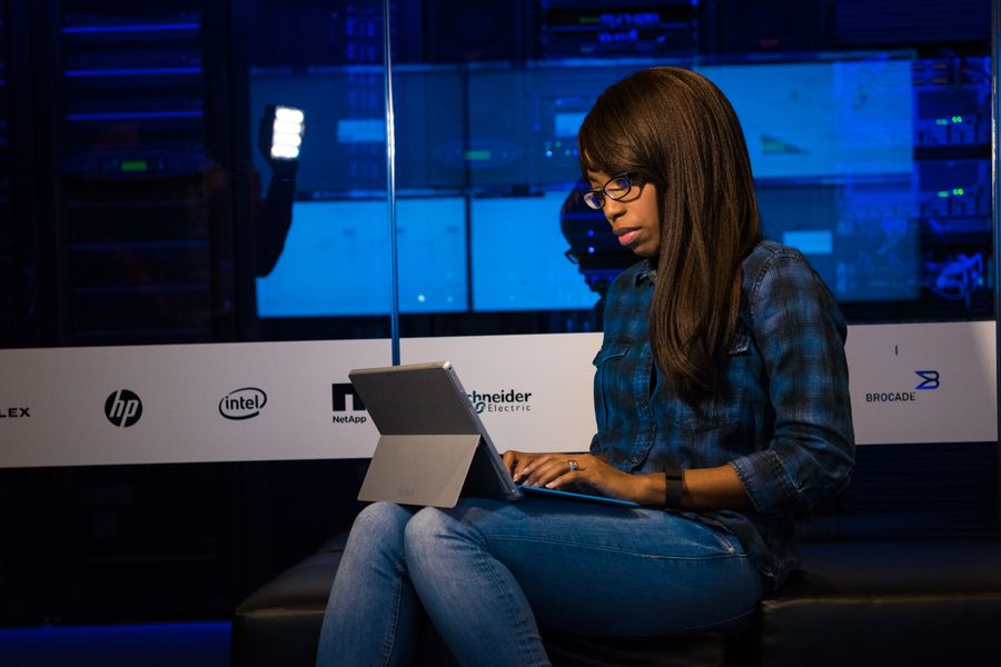 Woman working intently on a laptop in a modern data center environment.