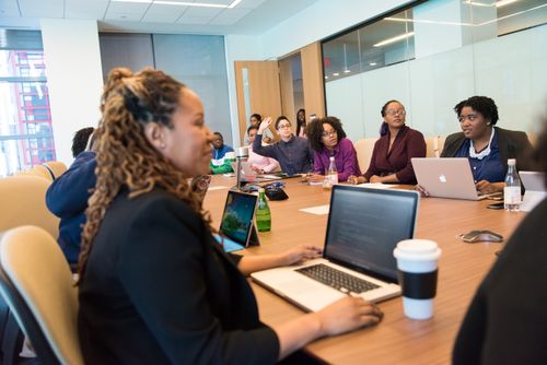 Free A diverse group of professionals engaging in a team meeting with laptops and discussions in a modern office setting. Stock Photo