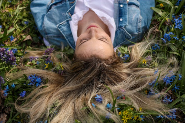 Woman Lying Down With Hair Entangled With Blue Flowers