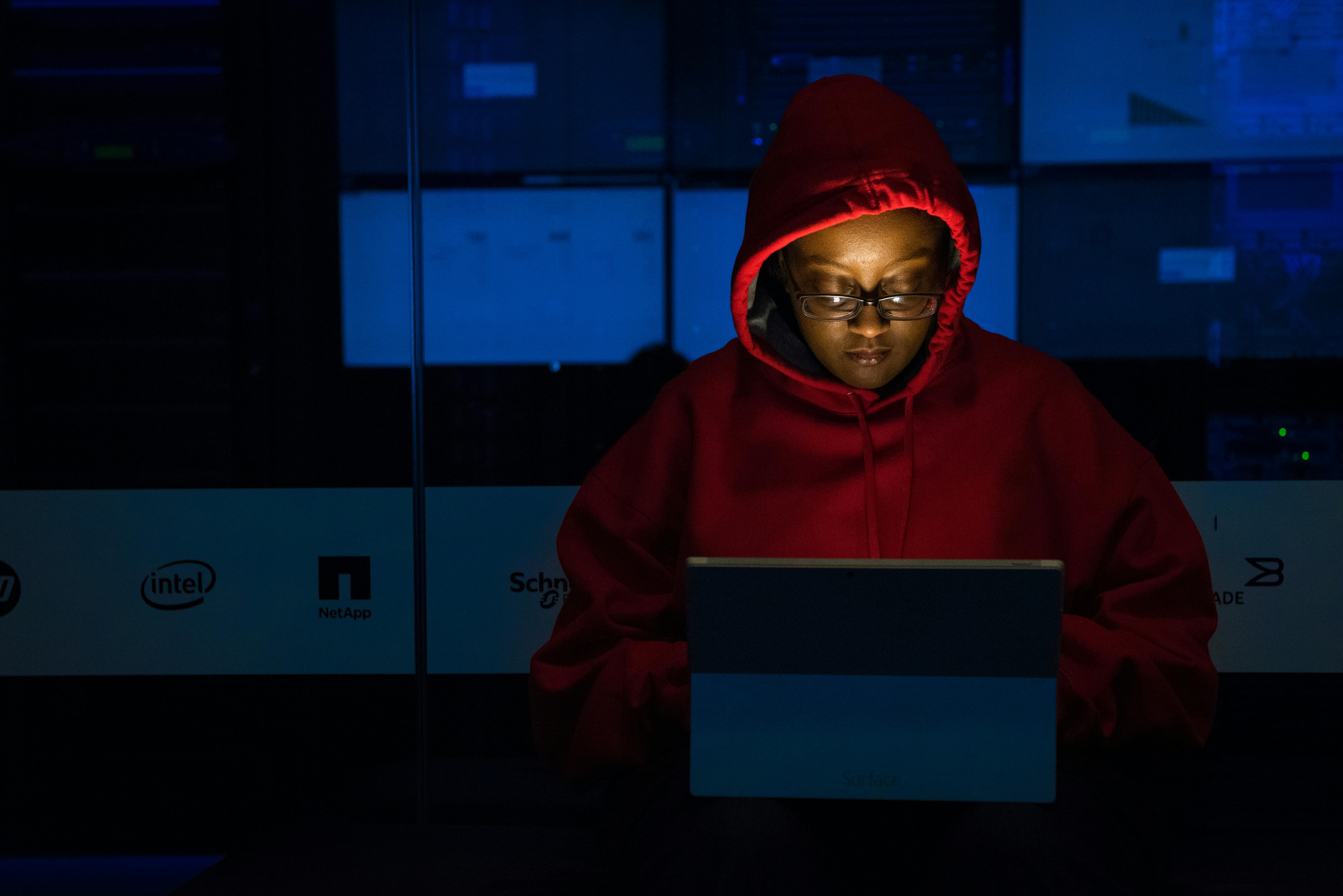 woman in red hoodie using gray laptop computer