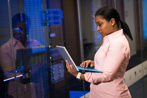 Photo Of Woman Holding A Gray Laptop In Front Of Systems 