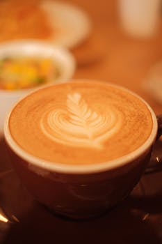 Enjoy a close-up of beautifully crafted latte art served in a cozy cafe setting.