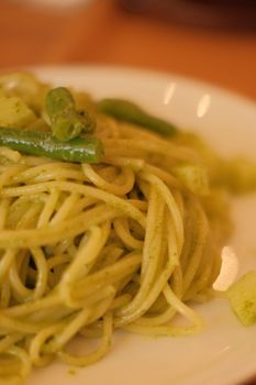Close-up of tasty green pesto pasta with vegetables, perfect for food photography.